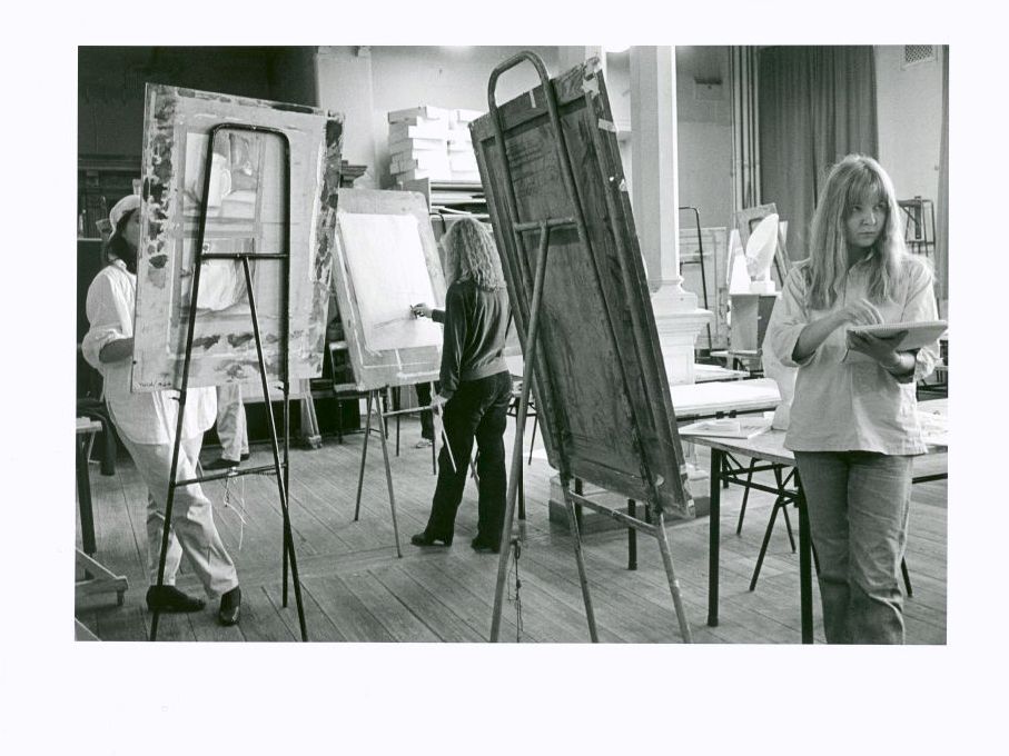 three students painting in class room