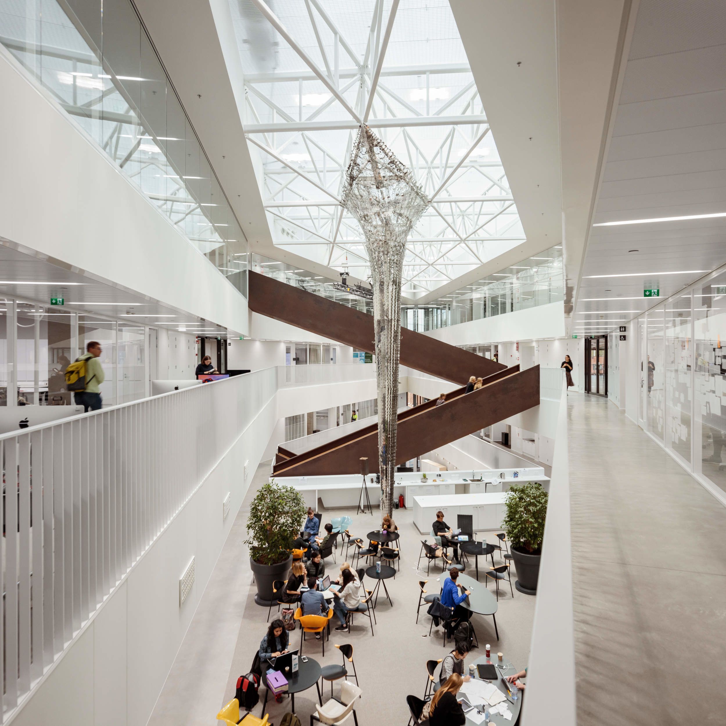 Picture inside the building, where you can see a metallic sculpture in the middle, reaching from floor to ceiling.
