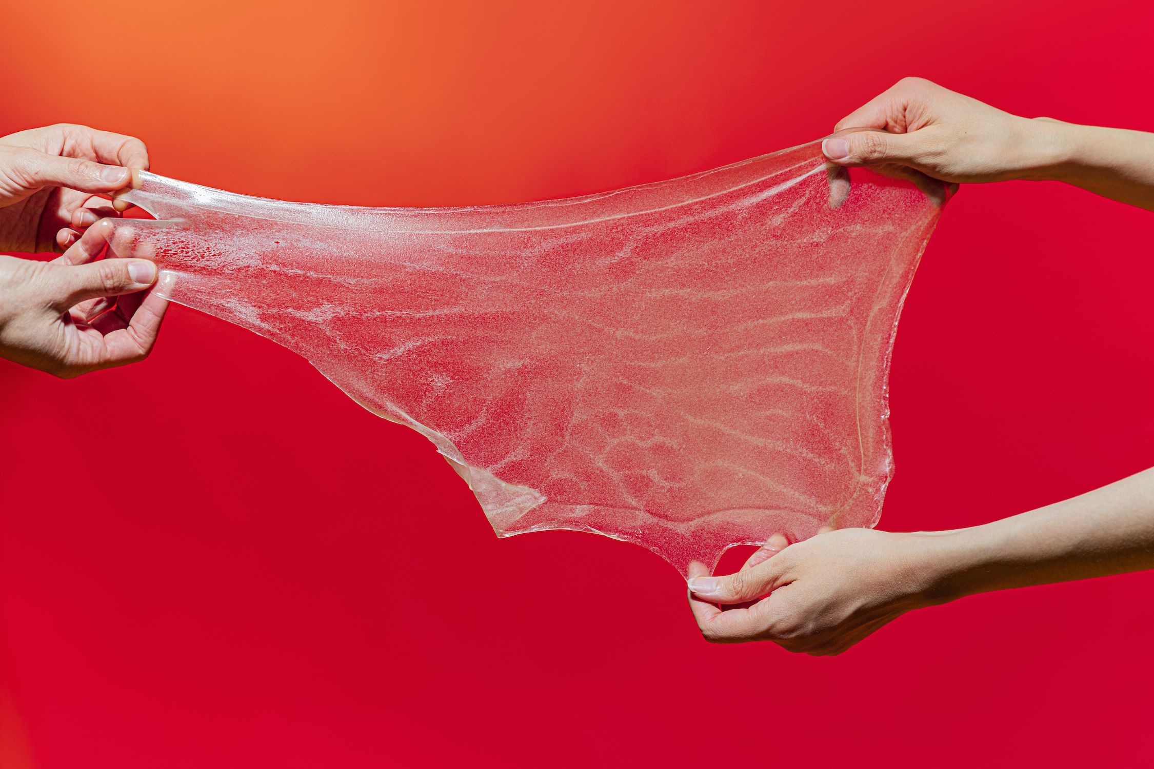 Bio Slime held by two people on a red background