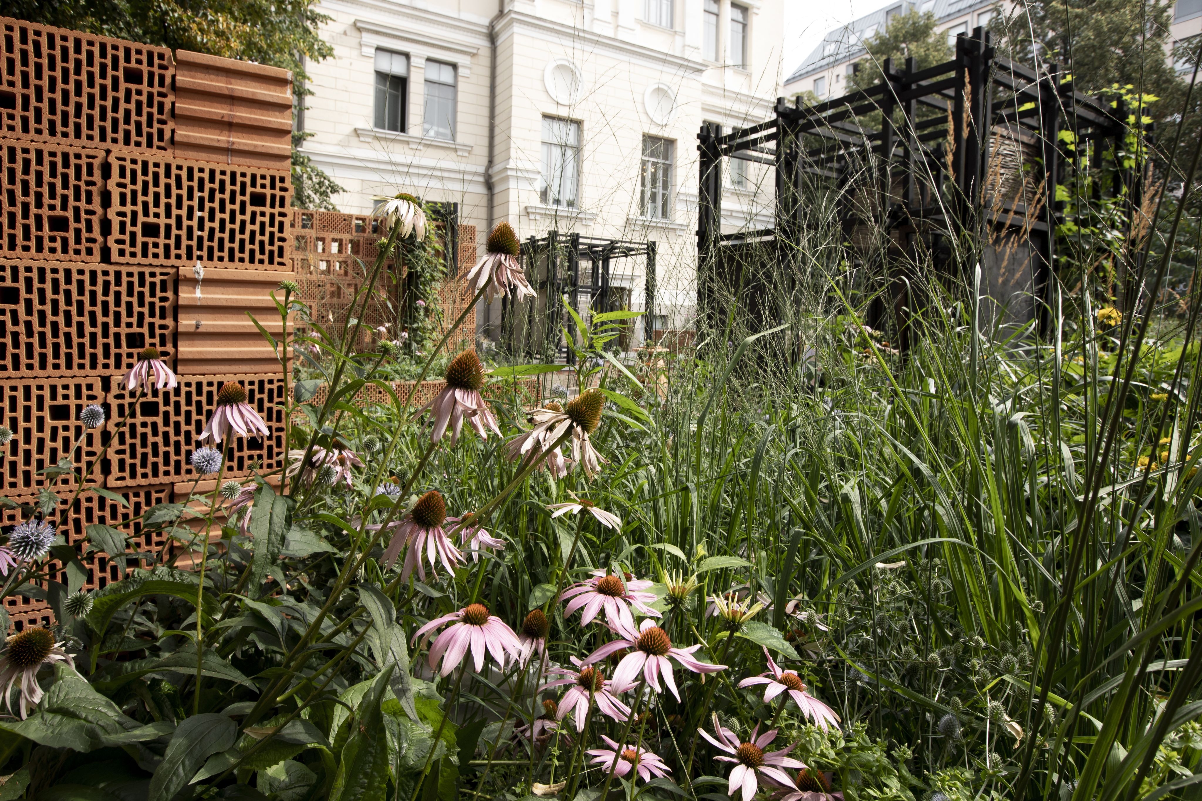 Paljon erilaisia kukkia tiiliseinän edessä.