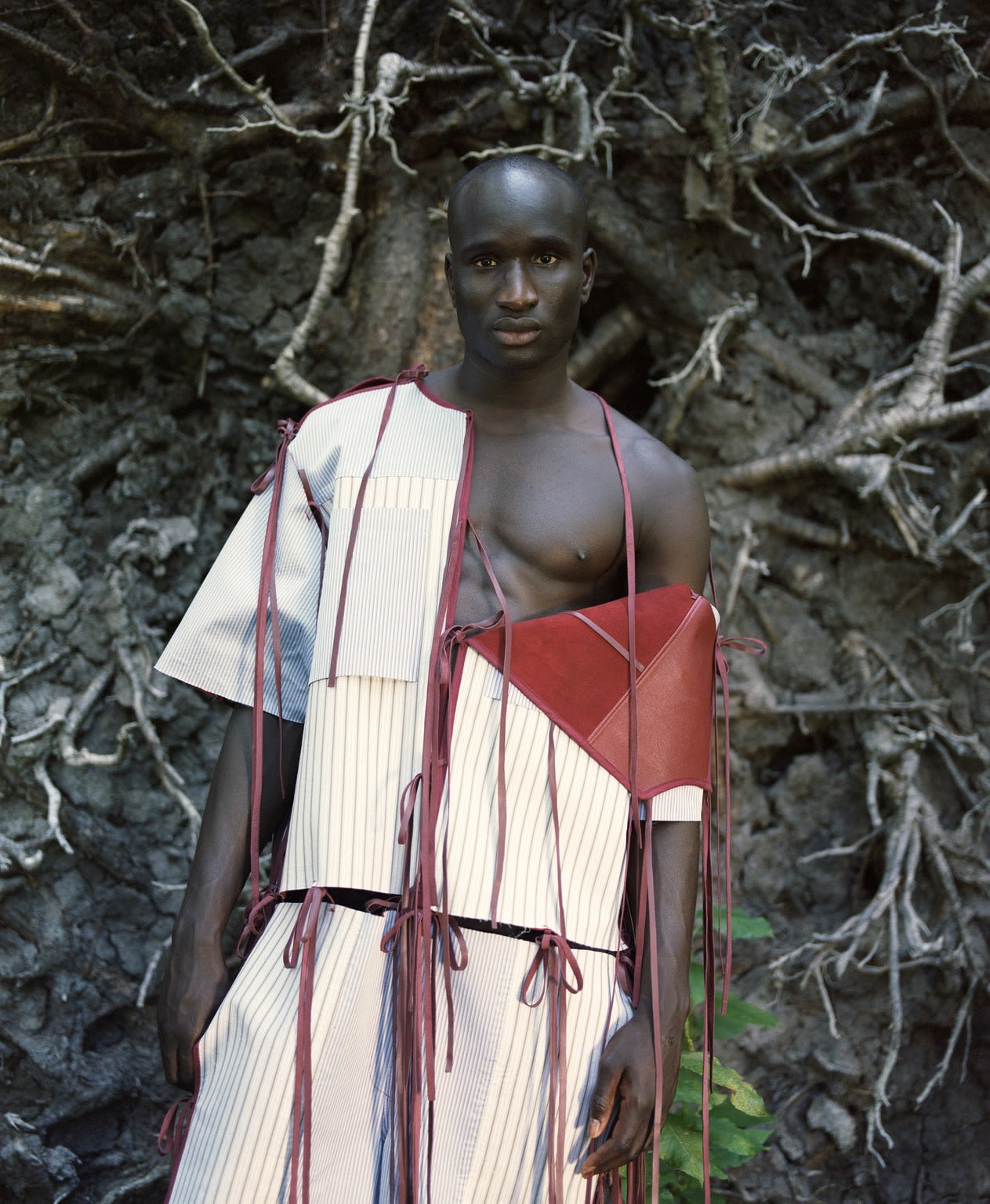 Black model wearing white and red garment in nature