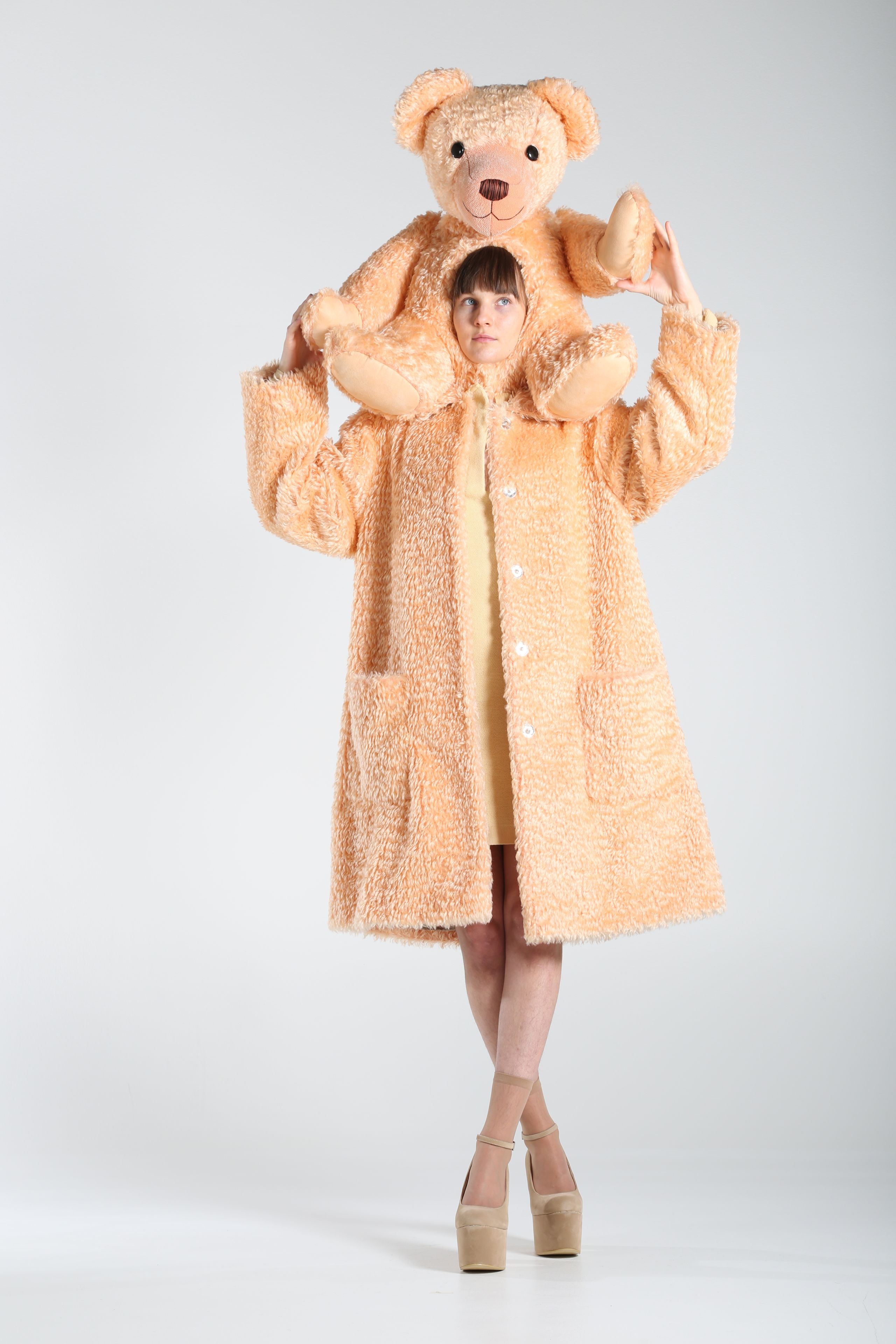model wearing beige soft teddy coat with a teddy bear attached to her head
