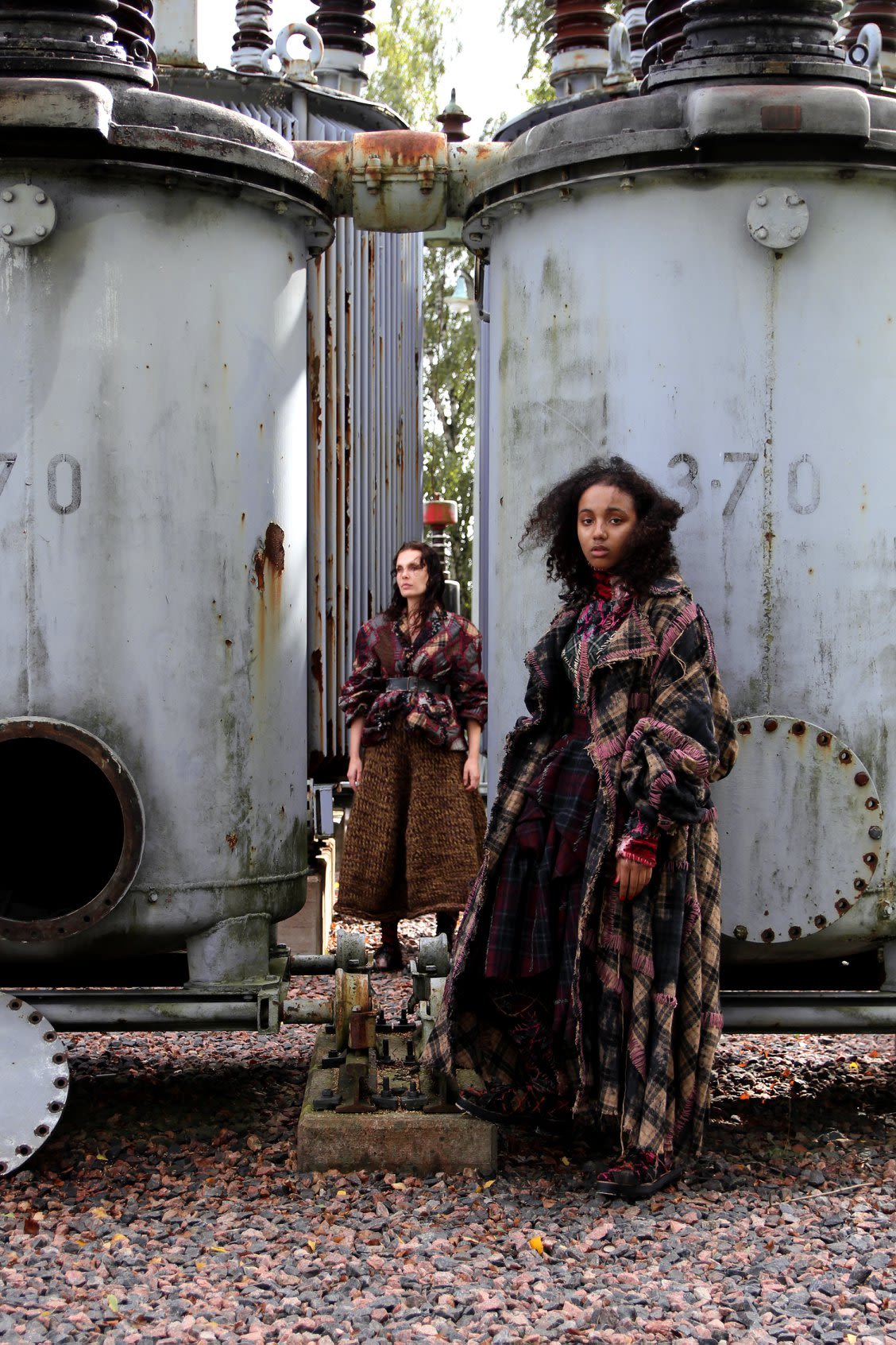two models wearing skirts and jackets in natural colors and textures in an industrial setting