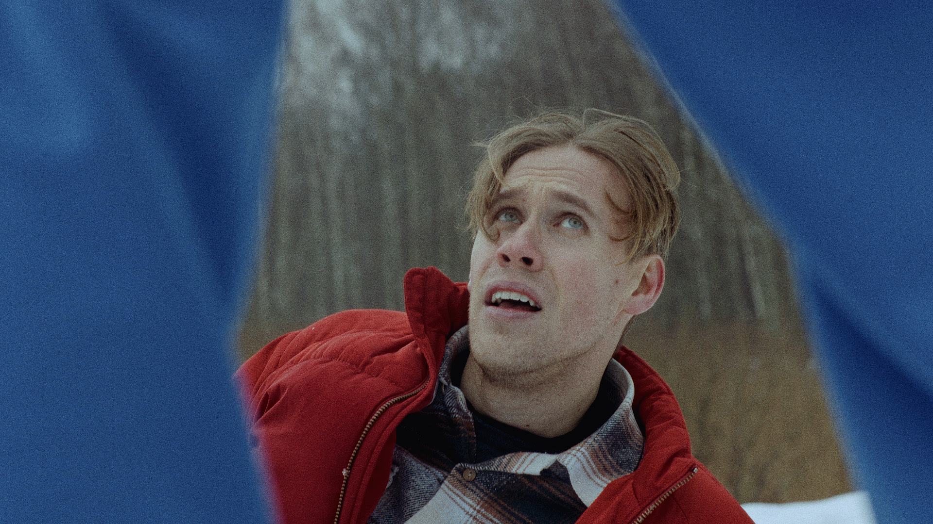 a man laying in the snow trying to get up while looking at another man