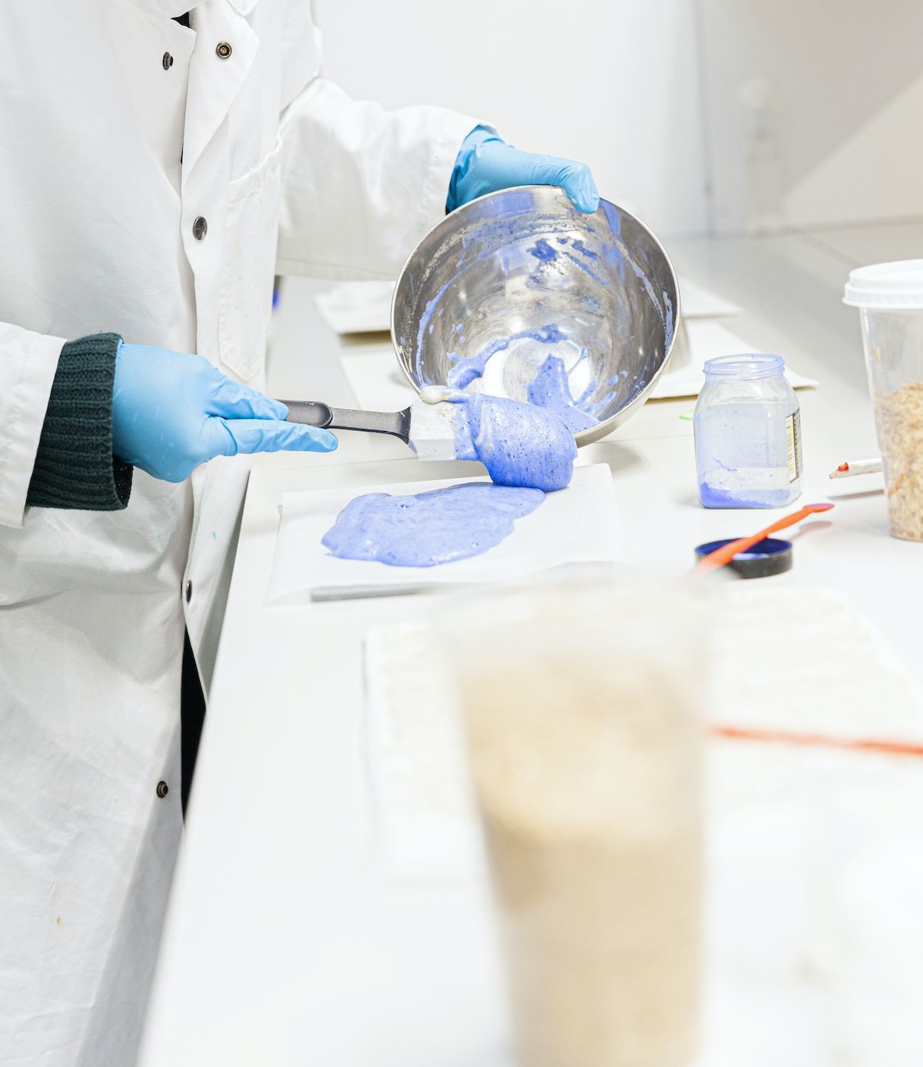 henkilö laboratorioympäristössä työstämäss sinistä vaahtoa