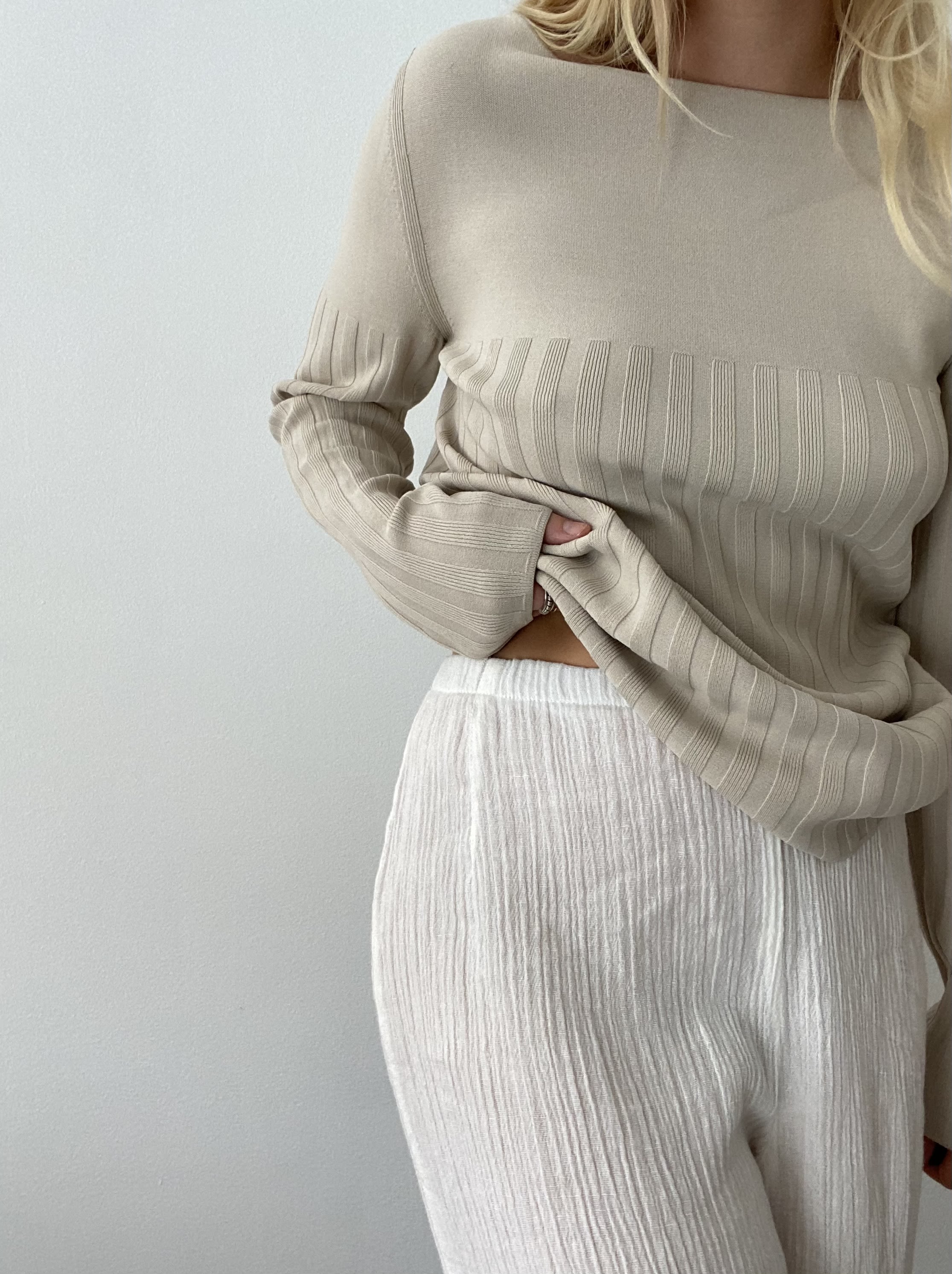 model wearing beige top with long sleeves and white pants
