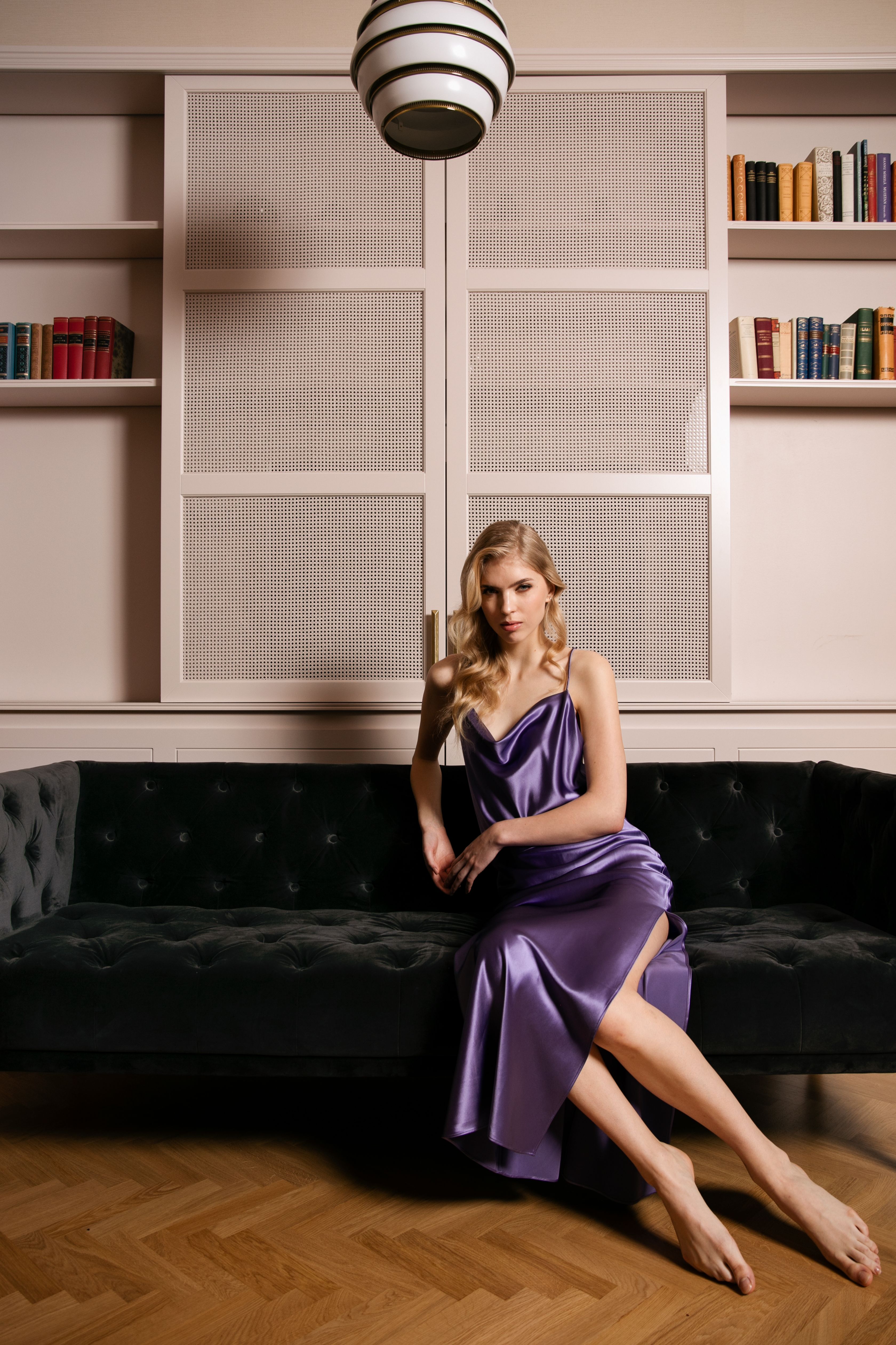 model wearing purple slip dress on dark couch